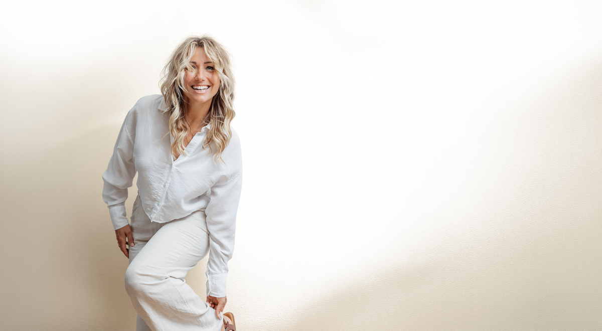 Michelle Derksen in het wit, lachend tegen een lichte muur